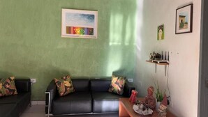 A living room with a green wall, a black sofa, and a wooden coffee table. - Pequizeiro Eco Pousada (Cavalcante)