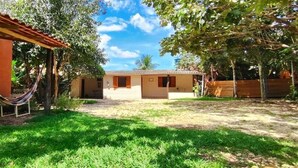 A house with a covered patio, a hammock, and a well-maintained lawn. - Pequizeiro Eco Pousada (Cavalcante)