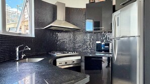 Una cocina moderna con un salpicadero de azulejos negros, electrodomésticos de acero inoxidable y un ventanal con vistas al exterior.