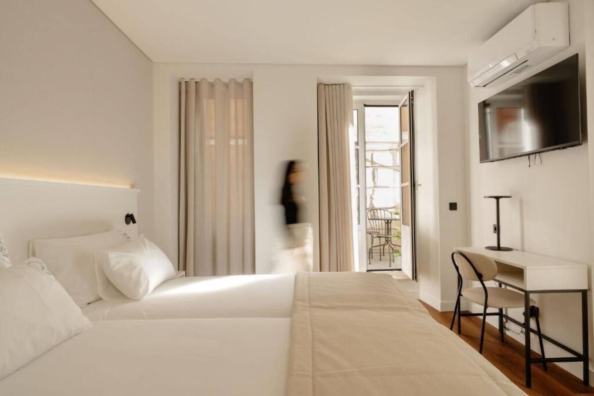 Una habitación de hotel moderna con cama, escritorio, televisor y vistas al exterior.