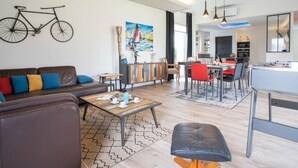 Un salon moderne comprenant un canapé, une table basse et un coin repas avec des chaises et une table.