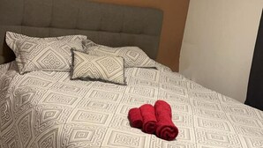 A bed with patterned bedding and two rolled towels. - Polar View Apartment (Tromsø)