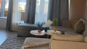 A living room with a sofa, a small round table, and a window with curtains. - Polar View Apartment (Tromsø)