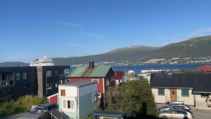 A coastal town with modern and traditional buildings, a cruise ship docked, and a view of the sea and mountains. - Polar View Apartment (Tromsø)