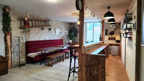 Ein rustikales Interieur mit einer Holzbank, einem roten Sofa und einer Küchenzeile mit Holzausbau und einer Bar.