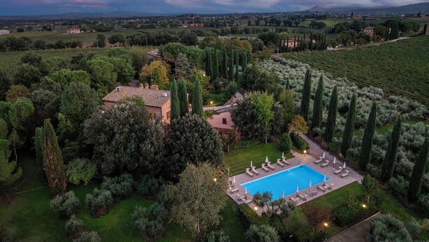Vista aérea de una villa con piscina rodeada de exuberante vegetación y viñedos.