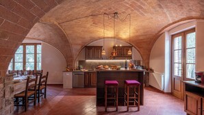 Una cocina amplia con techo de ladrillo, armarios de madera y una isla central con taburetes de bar.