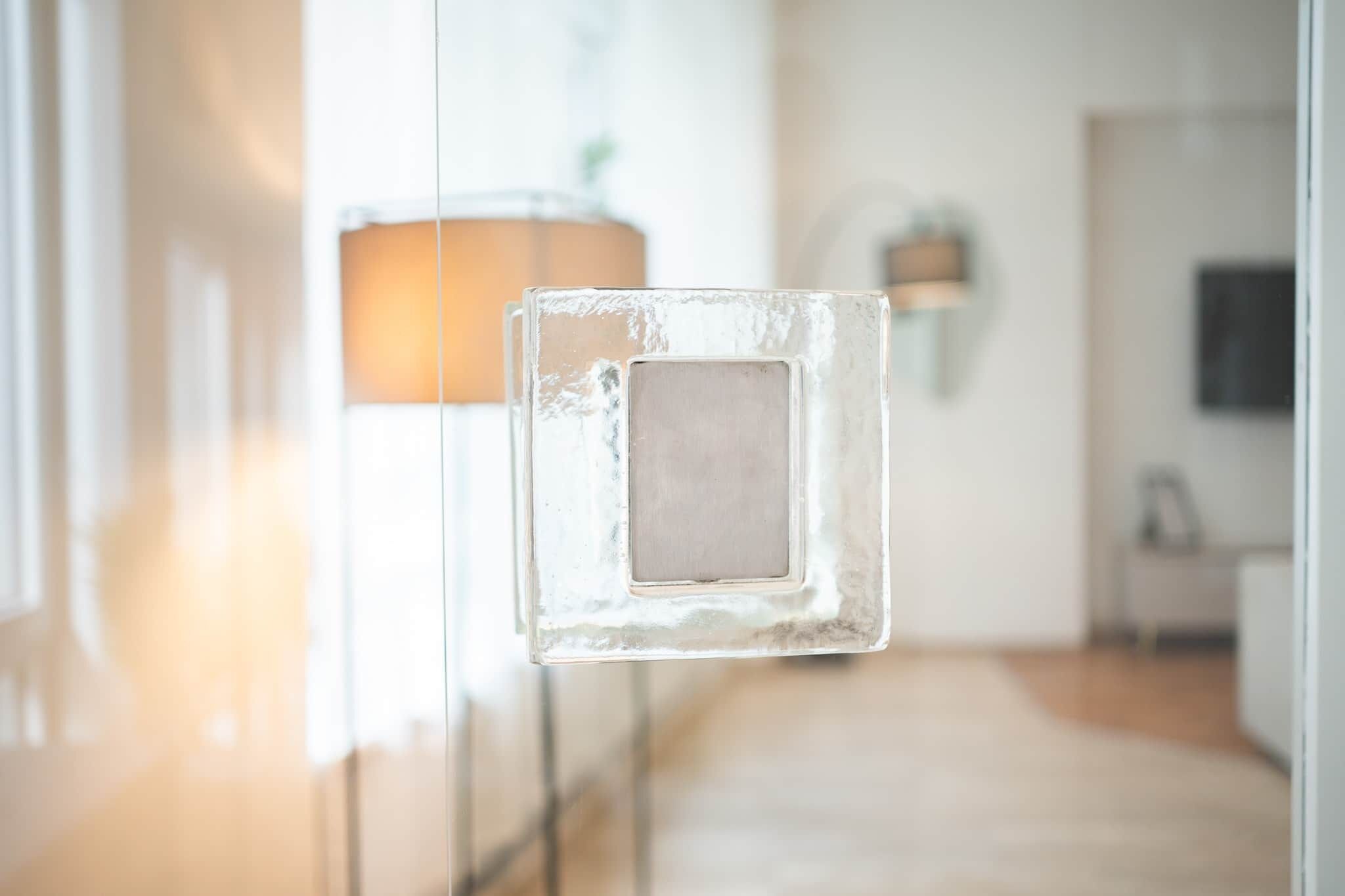 Et moderne interiør med en glasdør, en lampe og minimalistisk indretning.