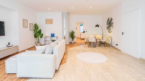 Una sala de estar moderna con un sofá, una mesa de comedor con sillas, un televisor y una planta.
