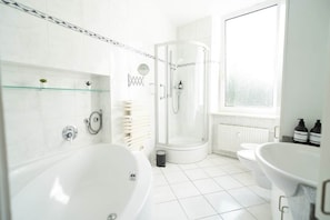 Ein modernes Badezimmer mit freistehender Badewanne, einer Duschkabine, einer Toilette und einem Waschbecken mit Spiegel.