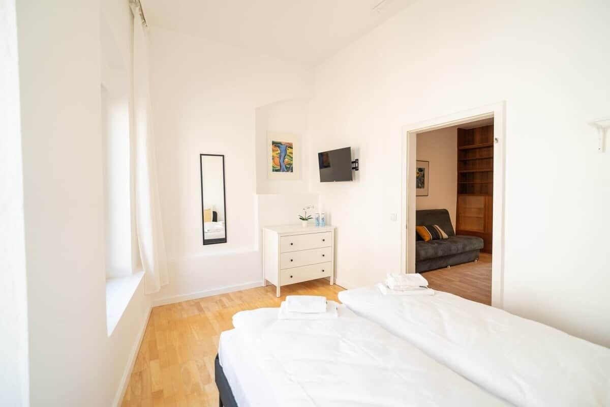 Un dormitorio con cama, cómoda, televisor y armario.