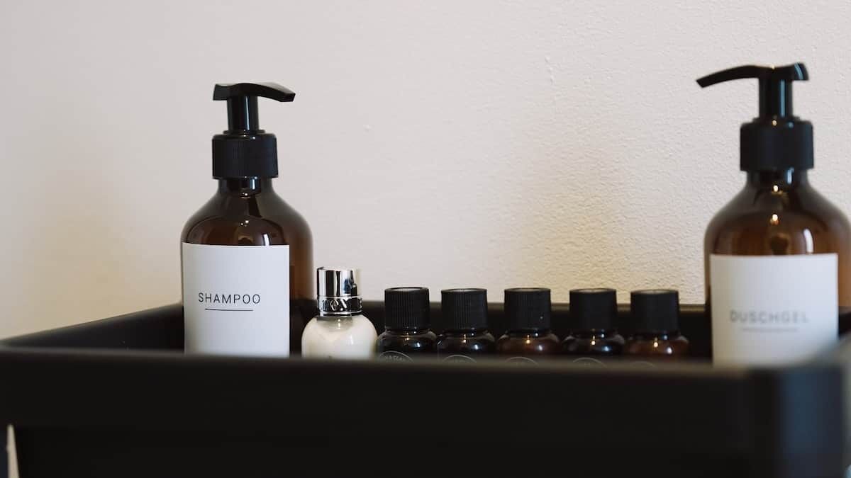Une étagère de salle de bain avec deux bouteilles de shampoing et une bouteille de gel douche étiquetée « DUSCHGEL ».