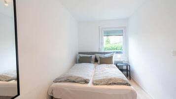 Un dormitorio con una cama, una ventana y una mesita.