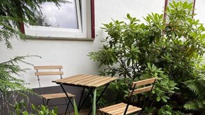Un espace extérieur aménagé avec une table et des chaises, entouré de différentes plantes et de rochers.