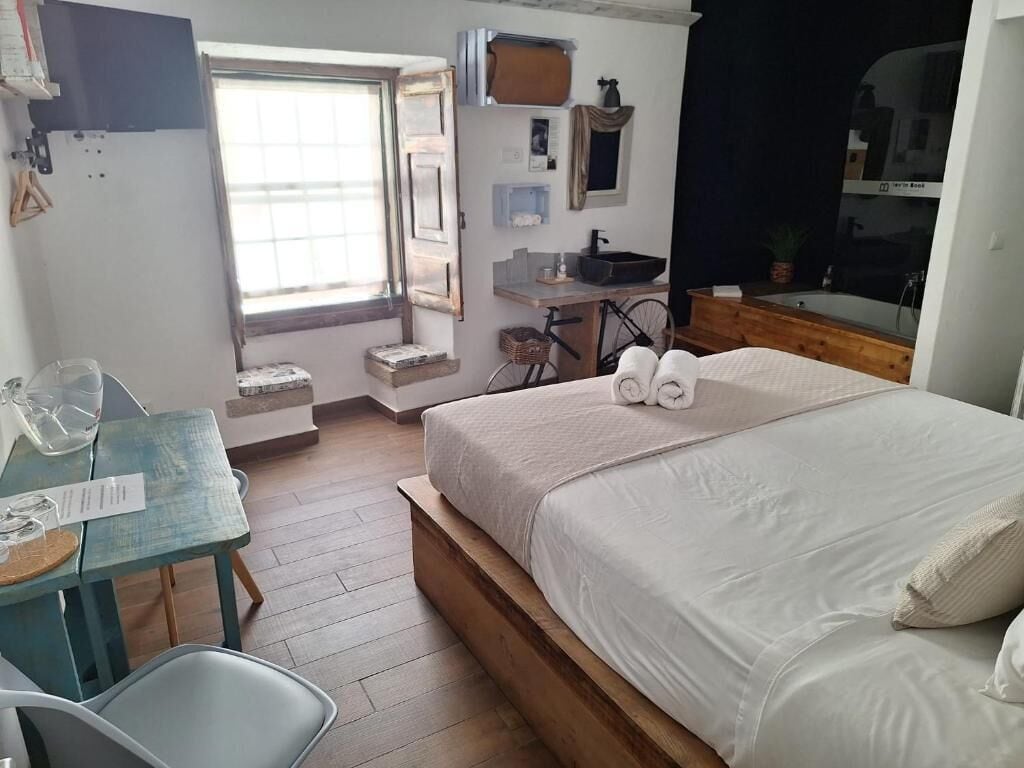 Quarto com cama, escrivaninha, bicicleta e janela.
