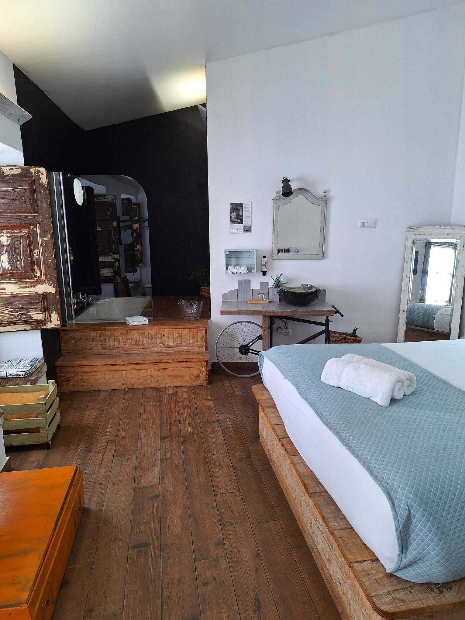 Una habitación con cama, cómoda de madera, bicicleta y espejo en la pared.