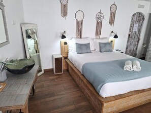 A bedroom with a wooden bed, bedside lamps, a mirror, a bowl on a table, and dreamcatchers on the wall. - Lovin Book Guesthouse (Óbidos)