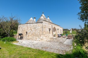 A stone building with a courtyard, outdoor seating, and a clear sky.