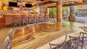 Ein Restaurant mit Barbereich, Holztischen und -stühlen.