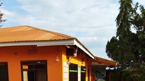 Un edificio con techo de tejas y un área de entrada pavimentada con plantas en macetas.