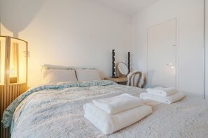 Un dormitorio con cama, tocador y espejo, y una puerta.