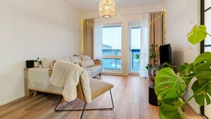 Ett modernt vardagsrum med en soffa, en tv och ett stort fönster med gardiner.