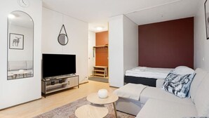 A modern living room with a flat-screen TV, a sofa, a coffee table, and a patterned rug. - Cozy Studio, Free Parking By Lapland Host (Rovaniemi)