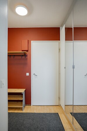 A room with a wooden bench, a white door, and a mirror reflecting the door.