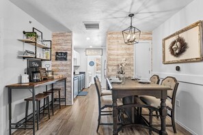 A modern kitchen with wooden shelves, a coffee station, and a dining area with a wooden table and chairs. - Ashley's Charming Chalet (Branson)