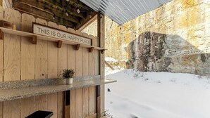 En yttervägg av trä med en skylt som lyder: ”DET HÄR ÄR VÅR PLATS DÄR VI HAR DET BRA” och en krukväxt på en hylla.