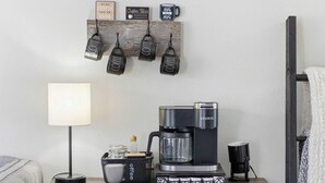 Eine Kaffeestation mit einer Keurig-Kaffeemaschine, einer Kaffeetasse, einer Kaffeemühle und einem Schild für die Kaffeebar.