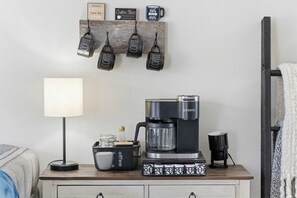 A coffee station with a Keurig coffee maker, a coffee mug, a coffee grinder, and a coffee bar sign. - TaneyCoMo Topia Quaint Studio (Branson)