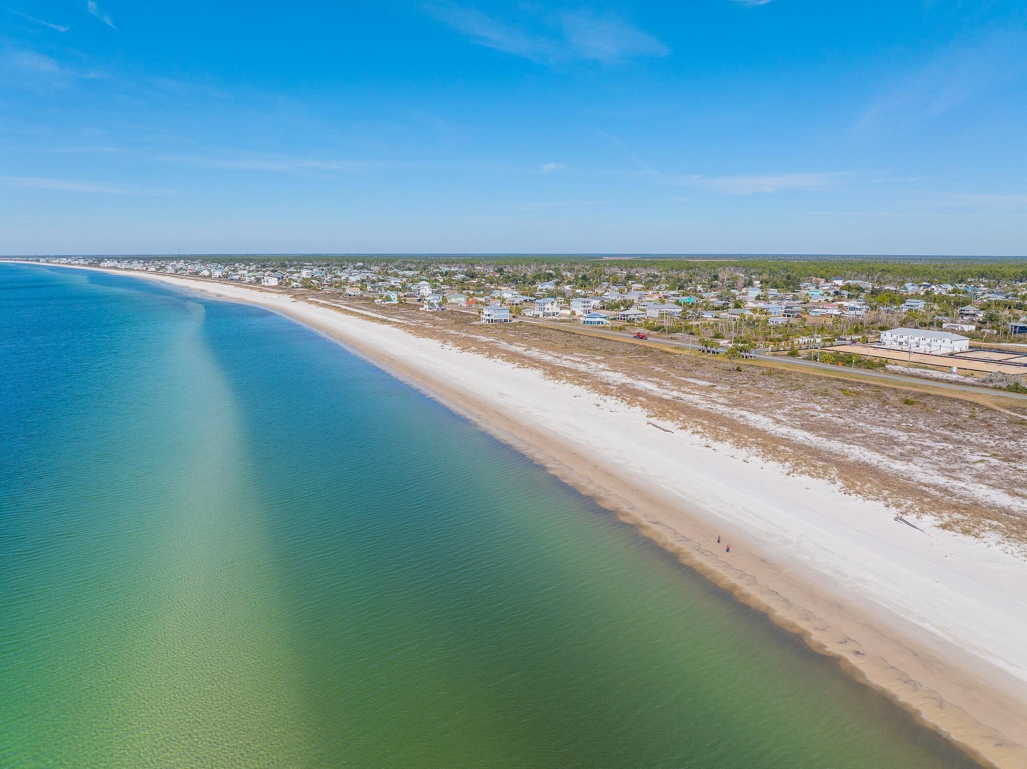 Oversigtsbillede af et kystområde med strand, huse og en vej.