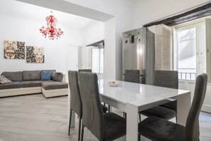 Eine moderne Küche mit einem weißen Tisch und Stühlen, einem Kühlschrank und einer Pendelleuchte.