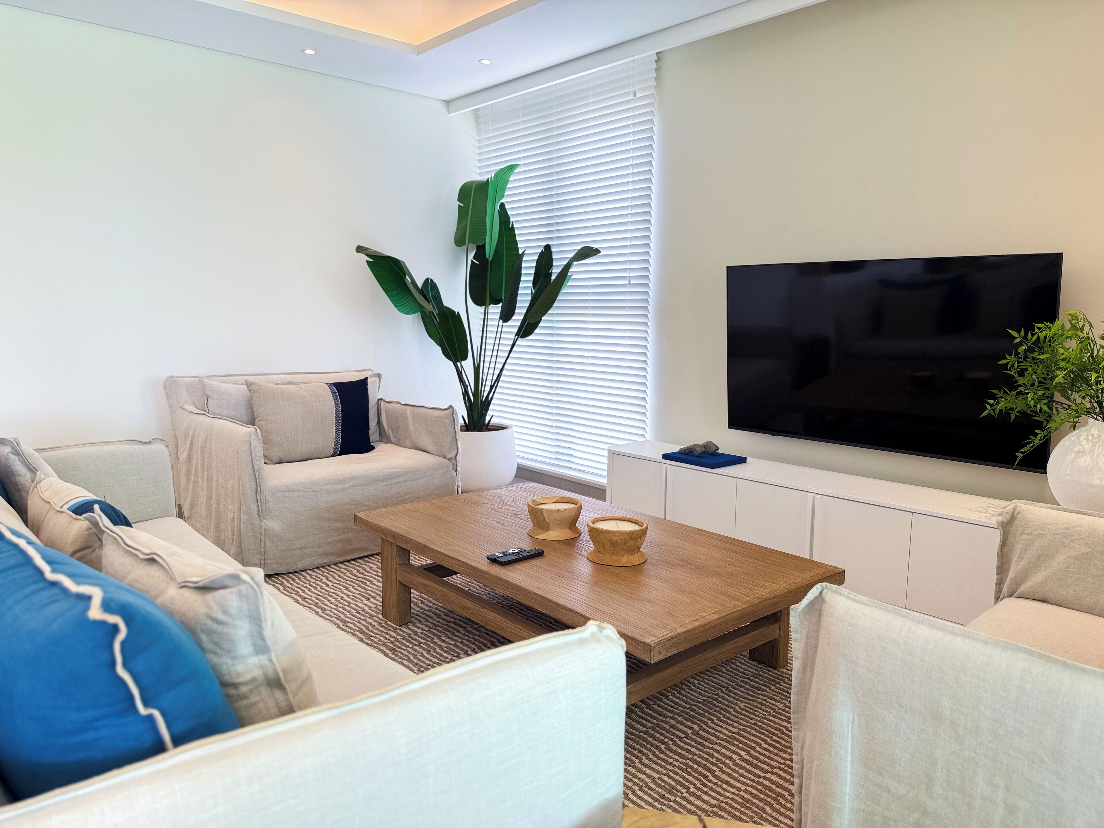 Uma sala de estar moderna com um sofá, mesa de centro e televisão de tela plana.