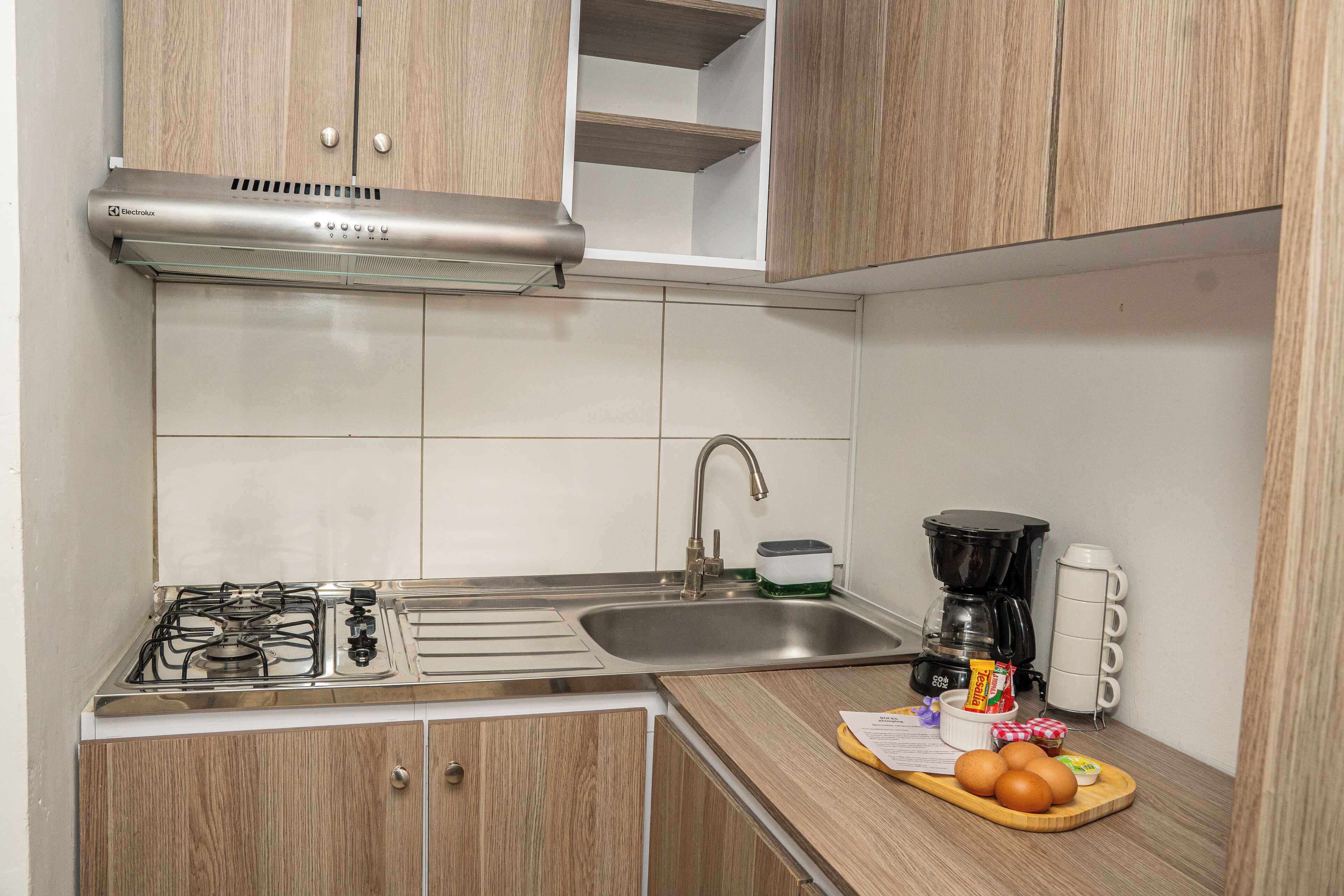 A kitchen with a gas stove, stainless steel sink, and wooden cabinets.
