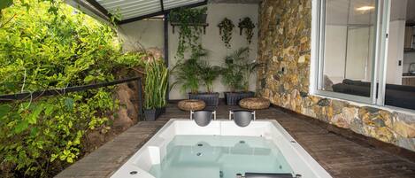 A spa area with a hot tub, surrounded by stone walls and potted plants.