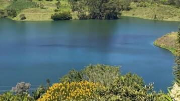 Ein See, umgeben von grüner Natur und Hügeln.