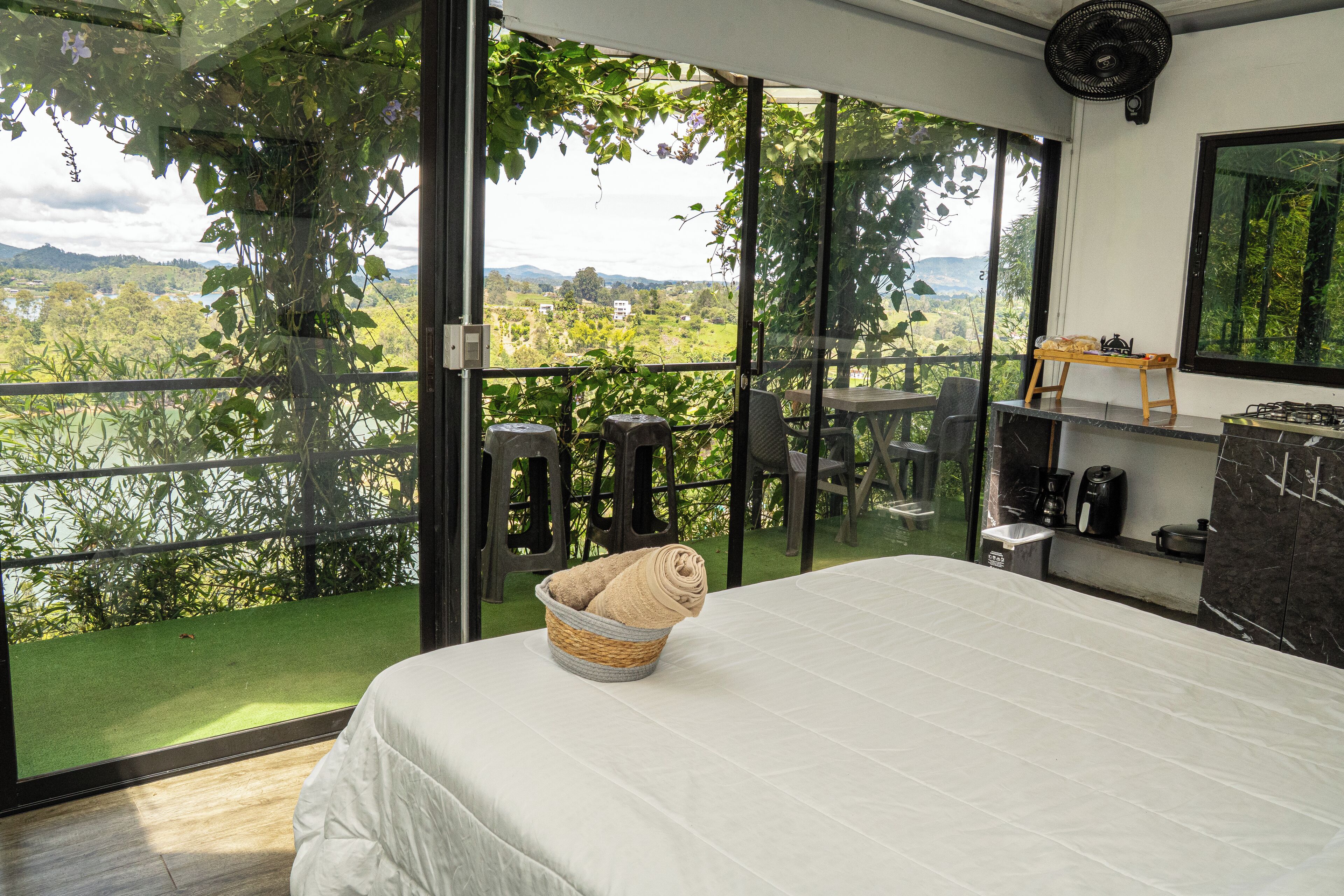 Une chambre avec un grand lit, une vue sur l’extérieur, une petite table et une chaise.