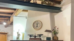 A fireplace with a clock above it, a vase with flowers, and a wooden staircase leading up to it. - Il Poggetto di Barbara - Casa Bianca (Scansano)