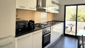 Una cocina moderna con armarios blancos, una estufa negra y una ventana con vistas a un balcón.