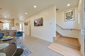 A modern living room with a dining area, a staircase, and a kitchen visible in the background. - Luxury New Build in Western District OKC for a large family (Oklahoma City)