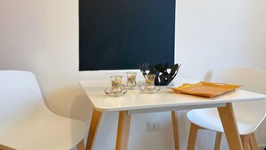 Ein weißer Tisch mit zwei Stühlen, eine Tafel an der Wand und ein dekoratives Objekt auf dem Tisch.