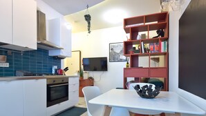 Eine moderne Küche mit weißen Schränken, einem eingebauten Backofen und einem Essbereich mit weißem Tisch und Stühlen.