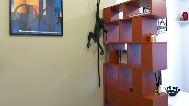 Ein Zimmer mit einer modernen, orangefarbenen Regaleinrichtung, einem gerahmten abstrakten Gemälde und einer schwarzen Skulptur.
