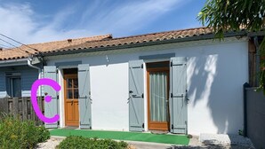 Una casa con tetto in tegole, pareti esterne bianche e due porte con persiane grigie.