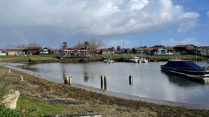 Una marina con barche ormeggiate, una zona verde con un sentiero e case sullo sfondo.