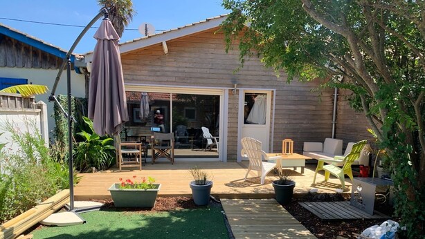 Una zona patio con pavimento in legno, mobili da esterno e piante in vaso.