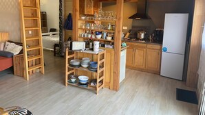 Una cucina accogliente con mobili in legno, un frigorifero e una dispensa con bicchieri.