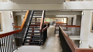 A multi-level interior with a central staircase, carpeted floors, and wooden railings.